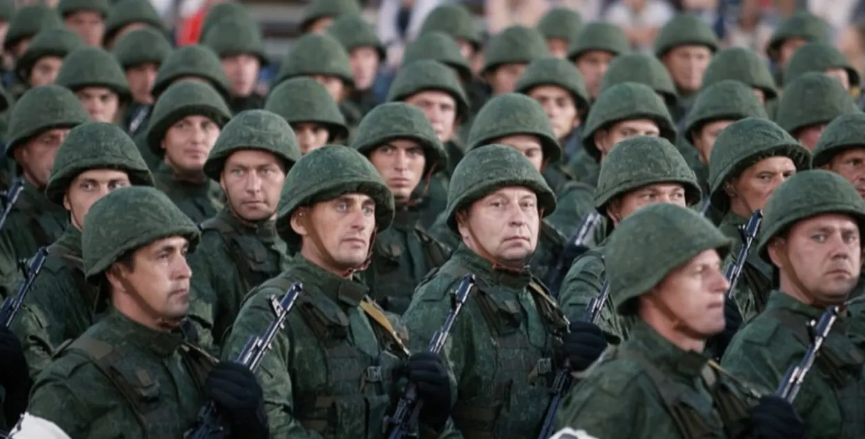 Плотный строй военнослужащих запаса в униформе с автоматами и в касках во время военного парада
