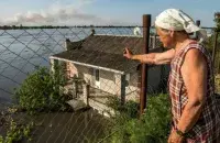Жительница Новой Каховки на Херсонщине смотрит, как вода затапливает соседние дома / Reuters
