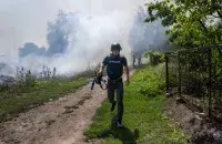 Дым после бомбардировки в Бахмуте за спиной журналиста / Bulent Kilic,&nbsp;AFP
