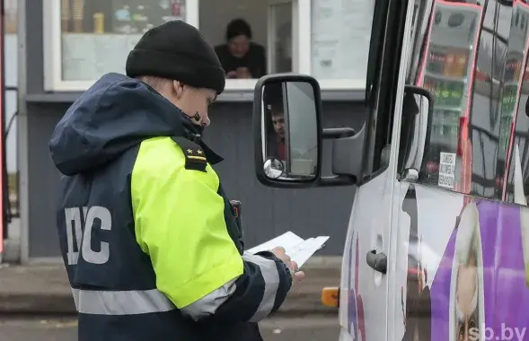 Супрацоўнік ДПС правярае дакументы ў кіроўцы маршрутнага таксі
