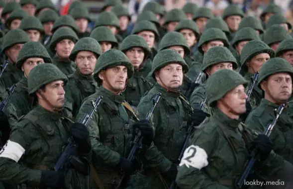Плотный строй военнослужащих запаса в униформе с автоматами и в касках во время военного парада
